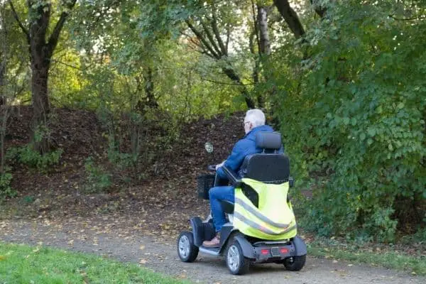 Man on mobility scooter traveling on forest trail