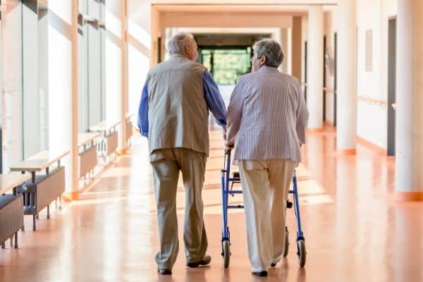 Two elderlies walking with one using a rollator