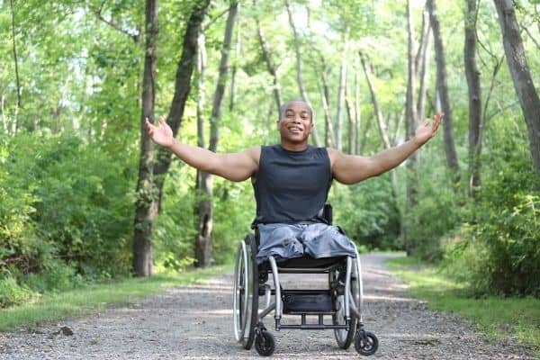 Healthy amputee on a wheelchair with trees on the background