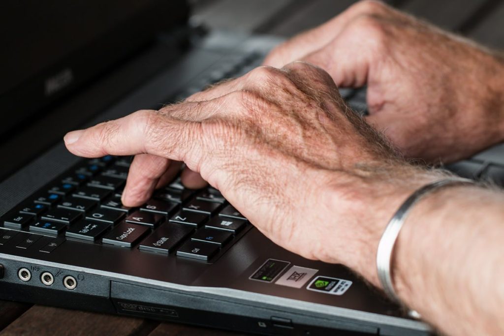 Older man hands typing email on a laptop