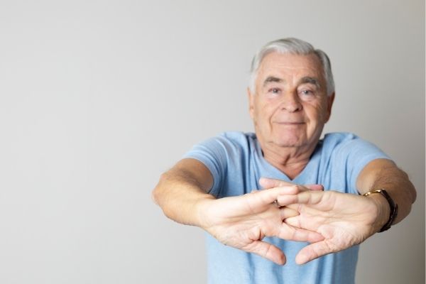 Elderly man stretching out arms and fingers