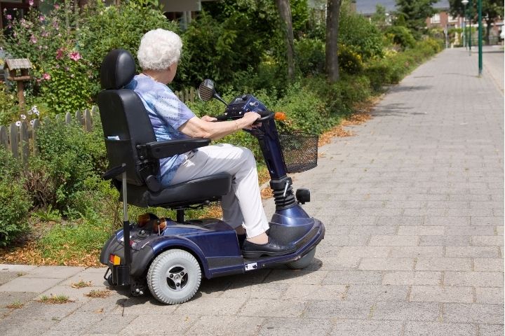 Elderly woman driving a three wheel mobility scooter